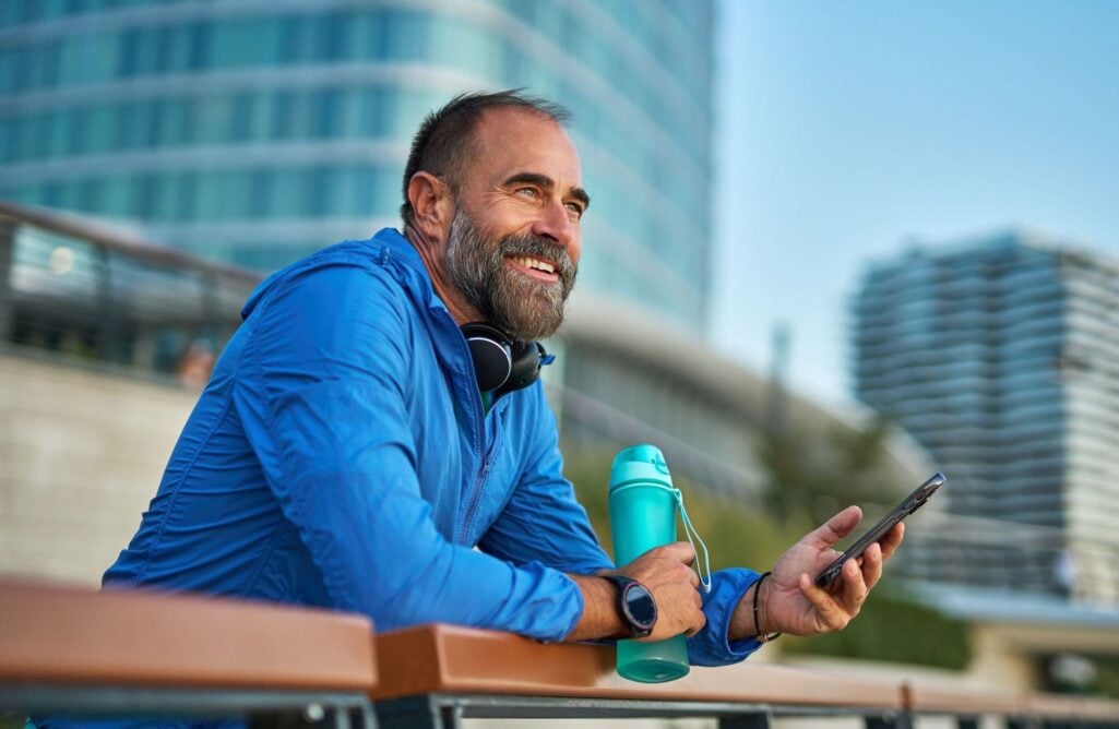 A smiling bearded middle-aged man looks over a vista as he considers building wealth after 50.