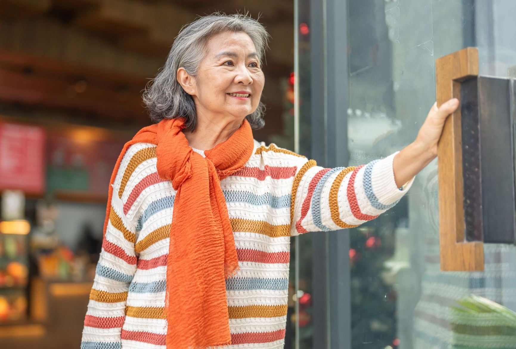 A smiling senior woman confidently enters a local shop, illustrating how smart budgeting and resourcefulness make living on social security alone a fulfilling and active chapter of life.