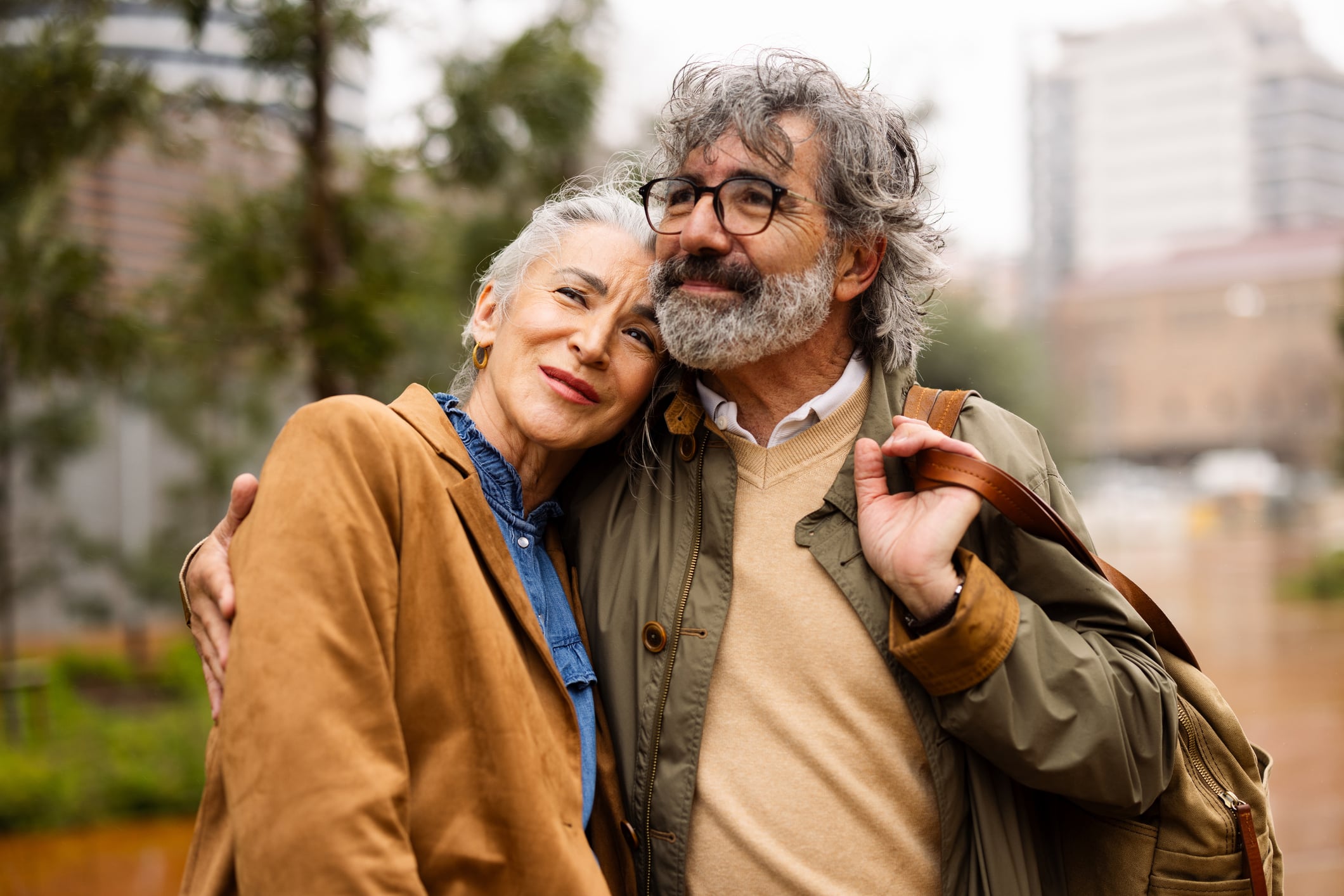An older couple stands close together in an urban park, illustrating how boosting financial literacy in america can provide security and peace of mind for the future.