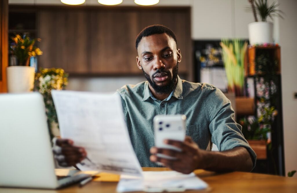 A middle-aged Black man at a table does research on annuity sales.